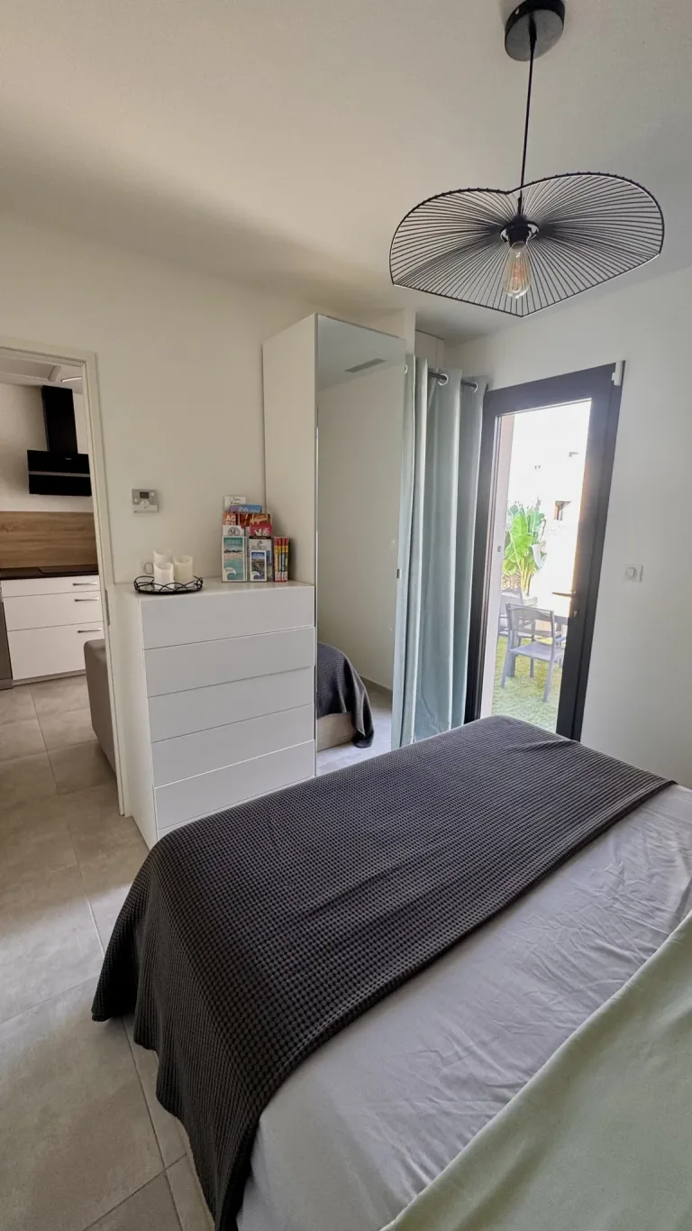 Chambre lumineuse avec lit et porte-fenêtre ouvrant sur la terrasse